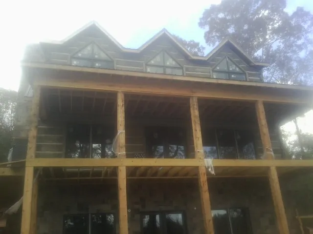 Dormers and porch framing on a large log home under construction — Roof Coating work by our crew in Molino