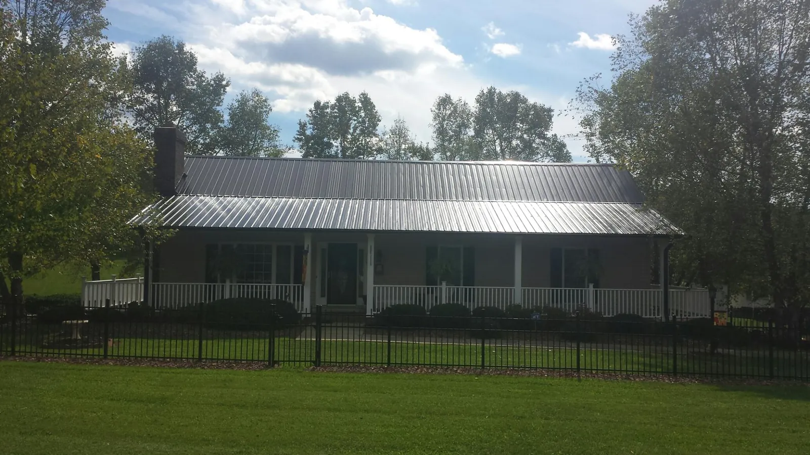 Gray metal roof on a brick ranch with a full width front porch — Gutter Guard Installation work by our crew in Molino