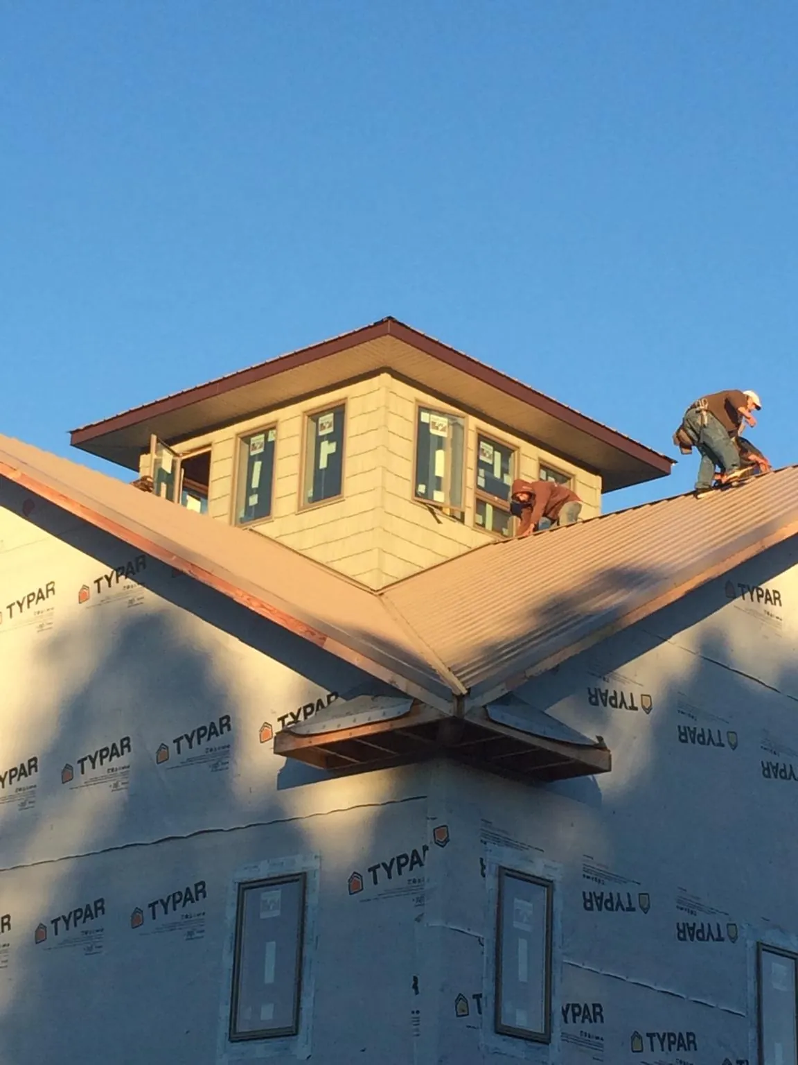 Roofers working around a rooftop cupola on a new metal roof at sunset — Roof Waterproofing in Molino by Roofing Brothers